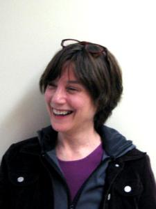 Headshot of Ellen Broselow Wearing a Purple Sweatshirt and Black Jacket Against a Light Background