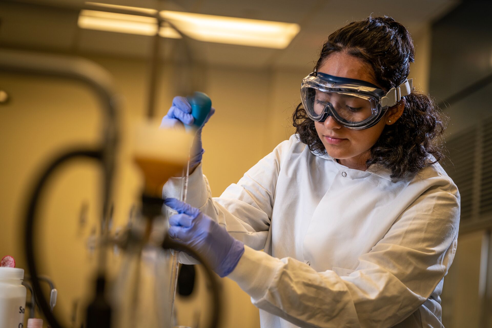 Student wearing gloves and goggles pipetting