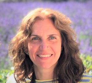 Arianna Maffei standing in front of purple flowers