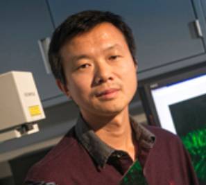 Headshot of Shaoyu Ge sitting in front of a computer screen