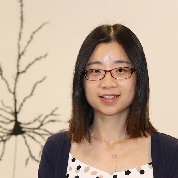 Xinxing Wang standing in front of neuron mural