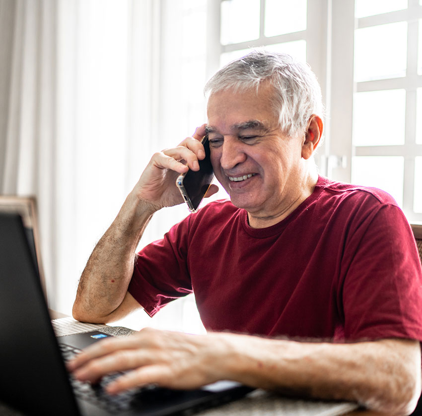 Main talking on the phone while looking at his laptop