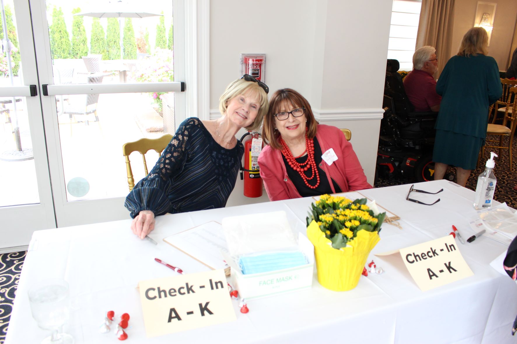 Two OLLI volunteers smiling behind a check-in table at an event