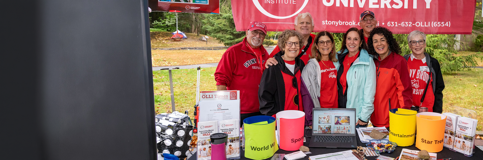 OLLI member at a registration table with other members in the background