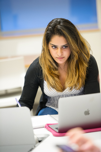 A student taking notes while working on her laptop