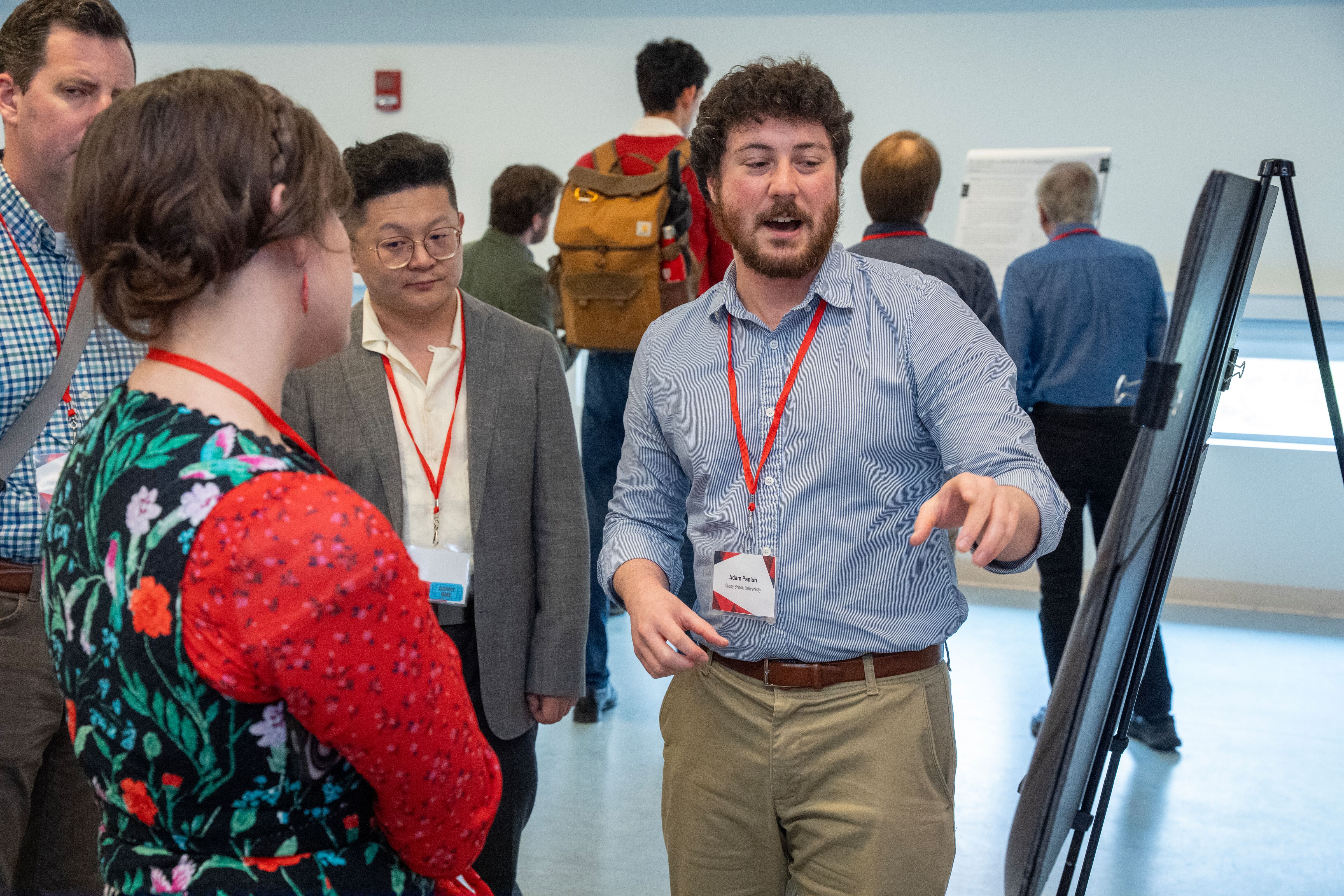 A man pointing at an easel while a small group listens.