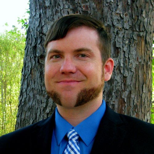 Headshot of Andrew Delton standing in front of a tree.