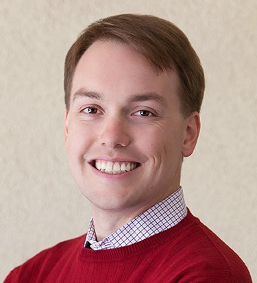 Headshot of Andrew Engelhardt in front of a beige background.