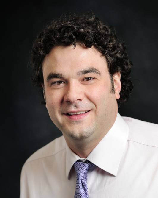 Headshot of Reuben Kline in front of a dark background.