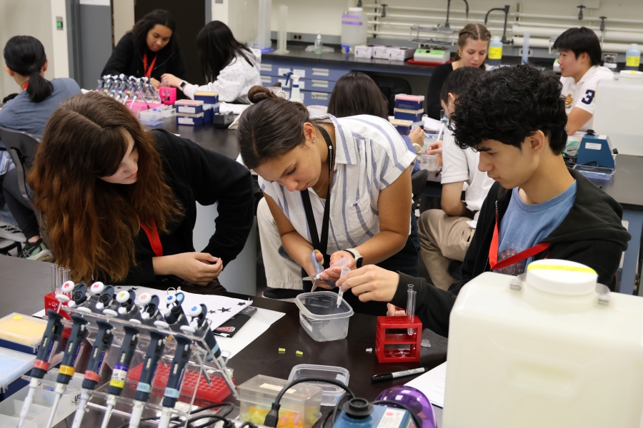 Students collaborating on a science experiment with tubes and lab equipment in a laboratory.