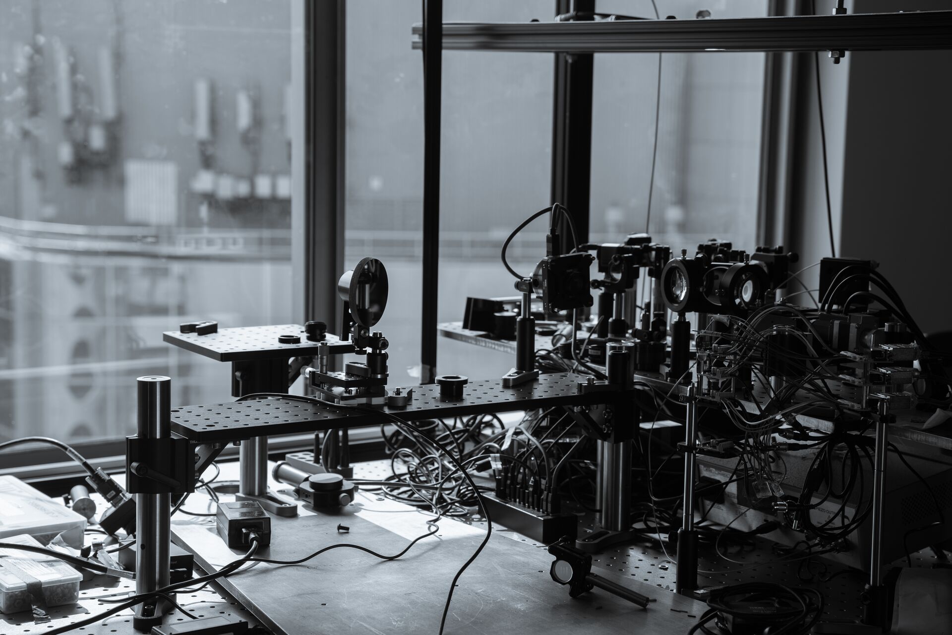Optical research equipment, including lenses, mirrors and precision mounts, arranged on a laboratory table with interconnected cables and instruments.