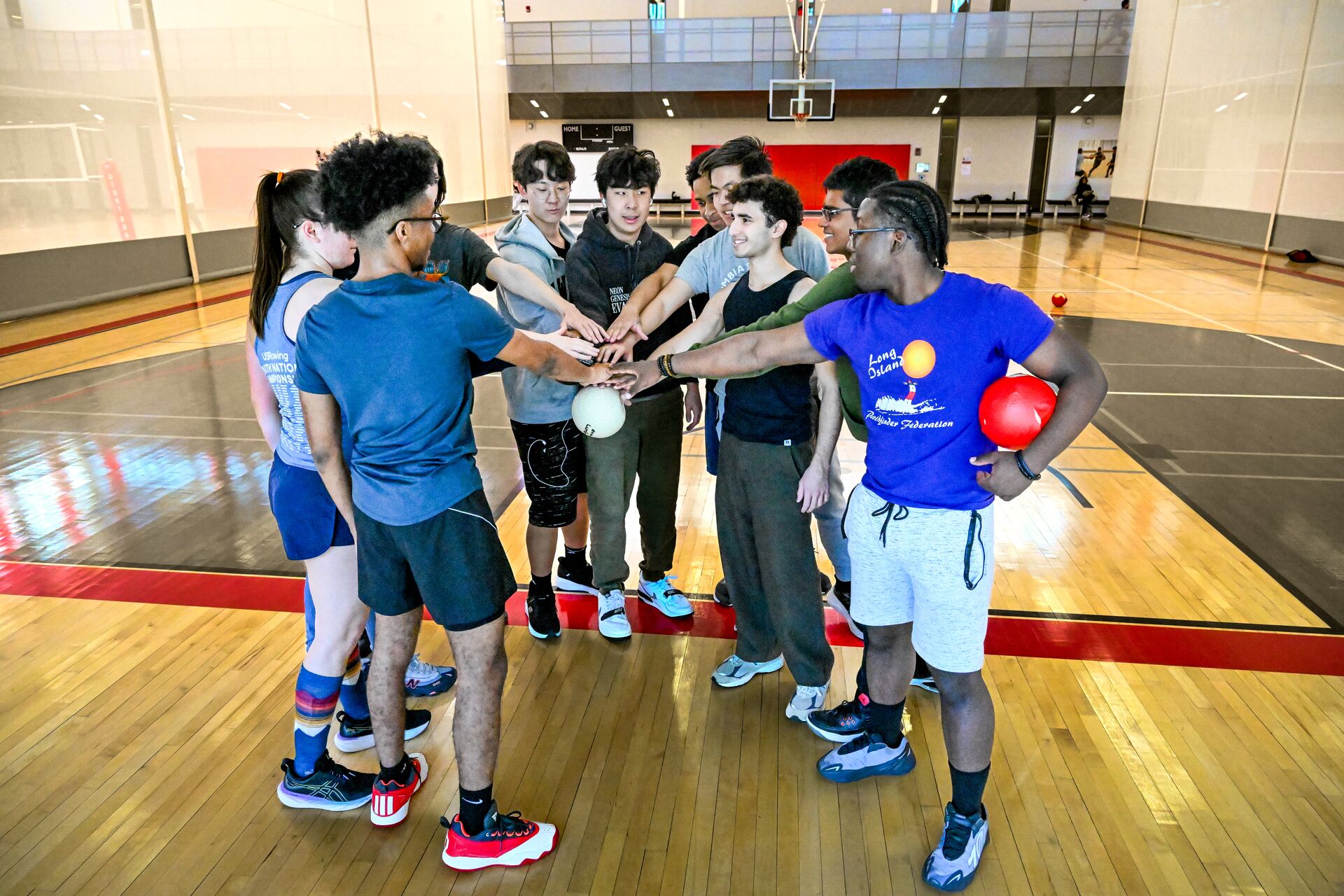 An intramural club putting their hands together on a basketball court.