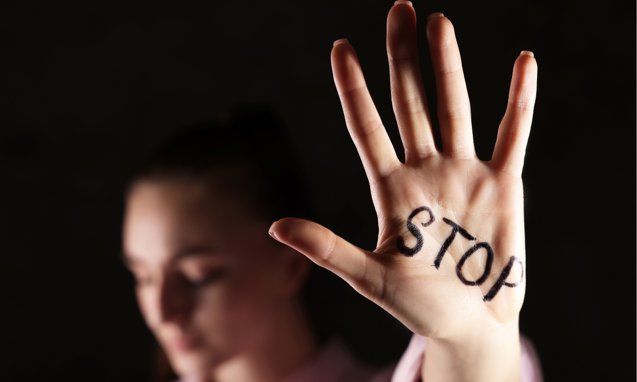 Woman holding up hand with STOP written on it