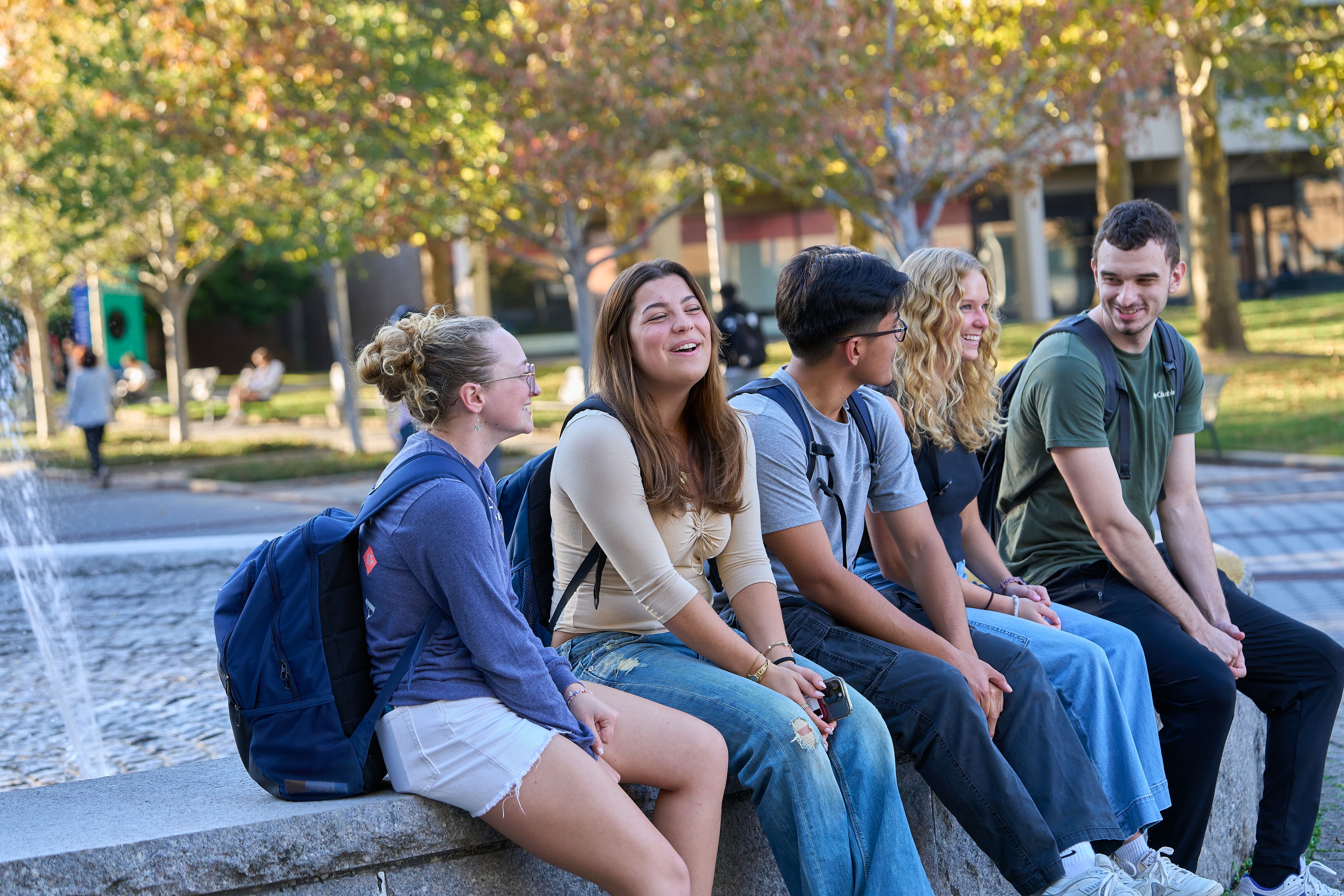 five students sitting on the edge of the fountain on the academic mall