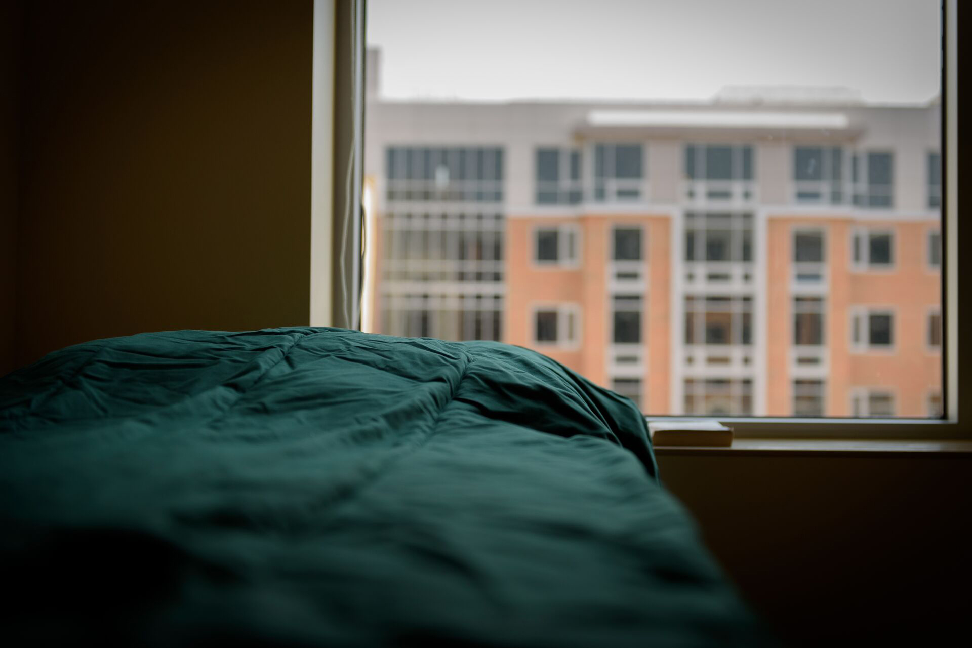 A bed beside a window where the outside view is Tubman residence hall