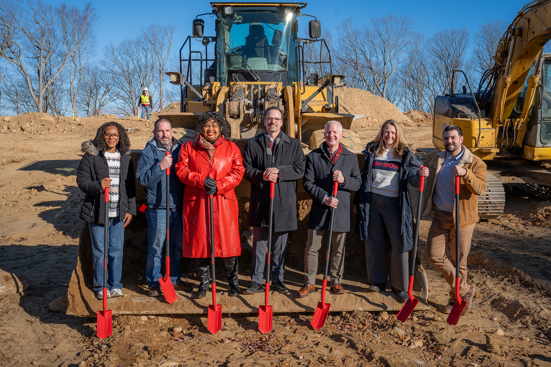 Campus Residences staff holding shovels beside construction equipment.