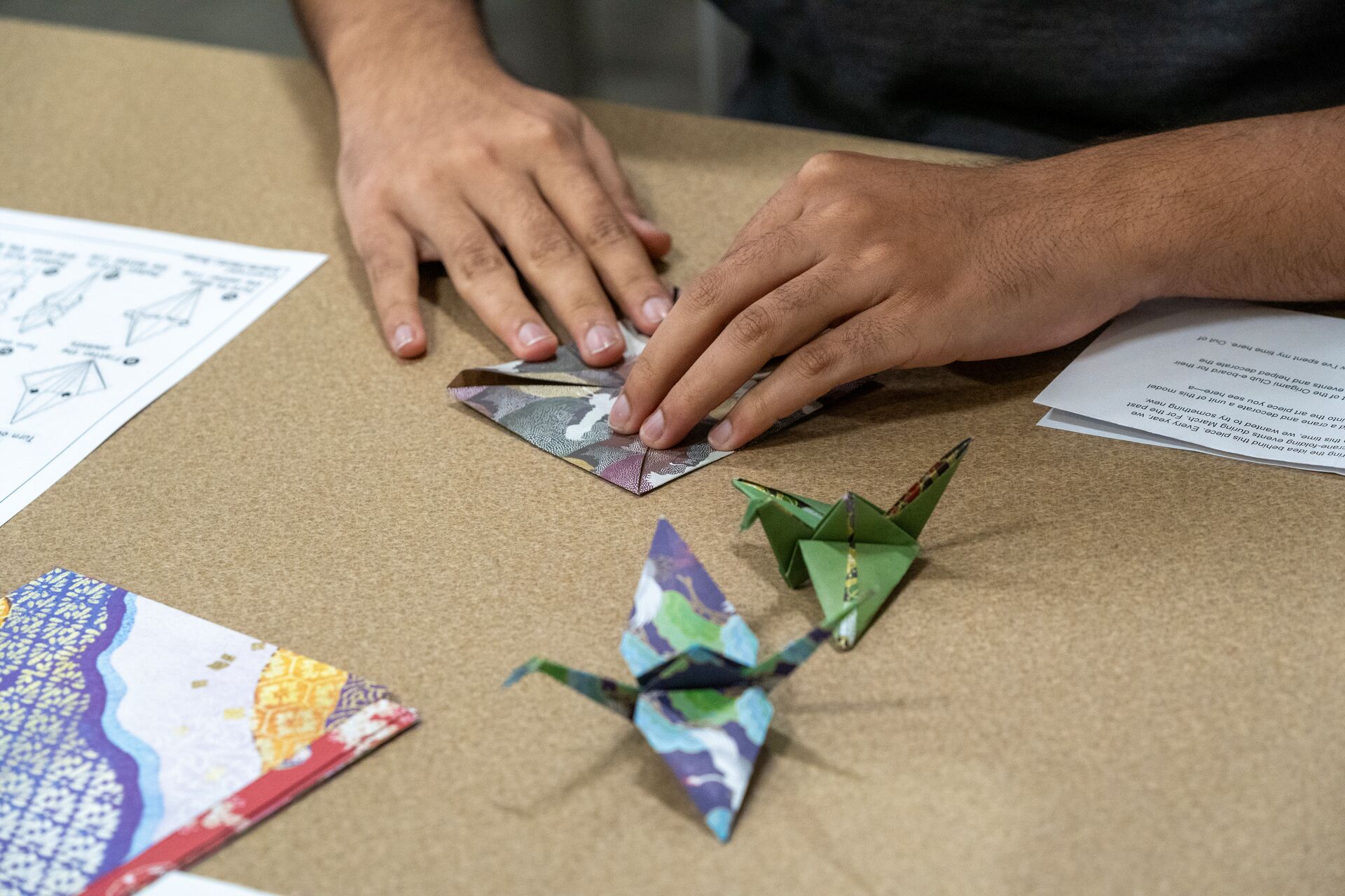 Hands folding origami paper.