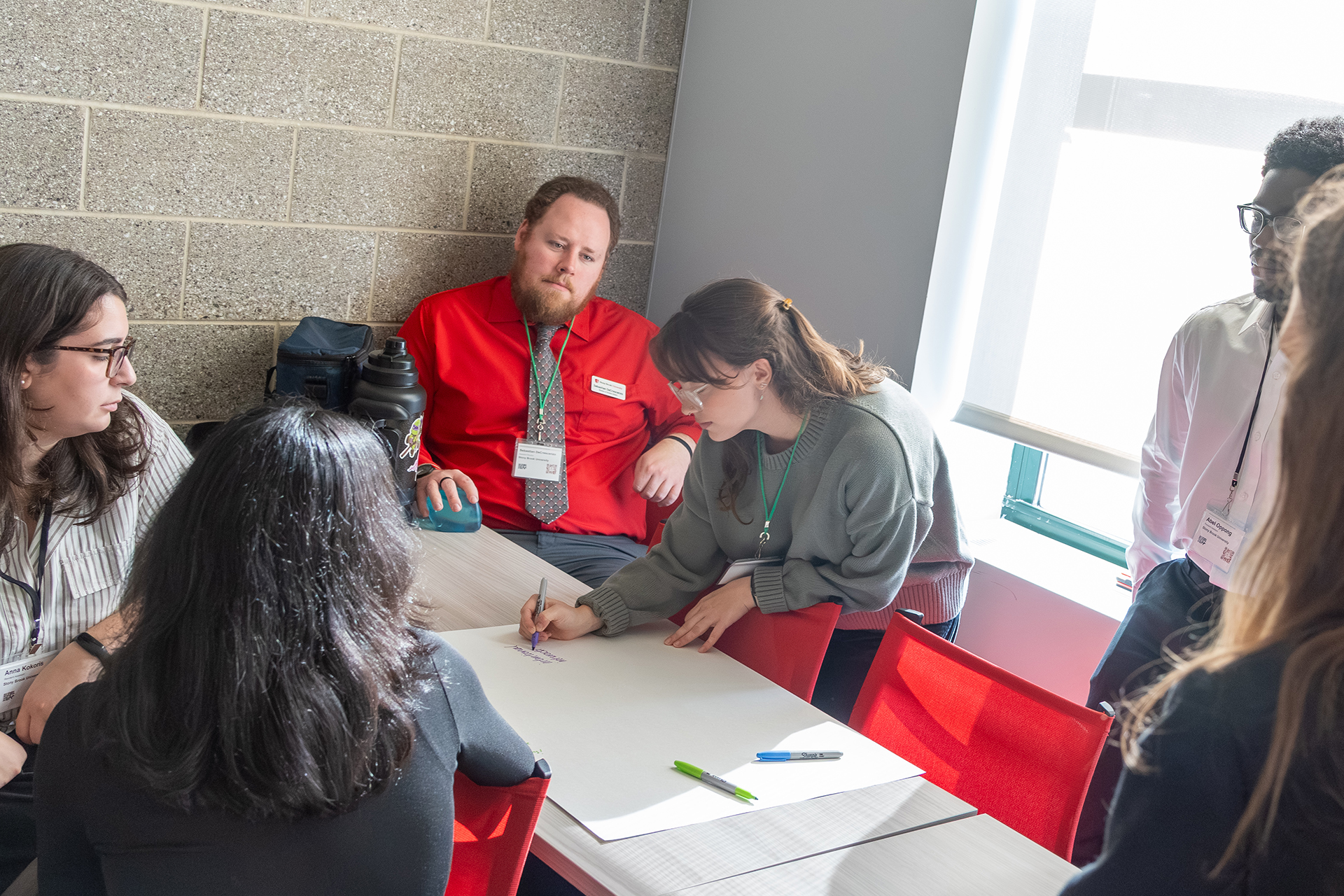 A group watching someone write on poster paper.