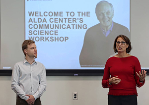 man and women in front of slideshow screen about Alan Alda