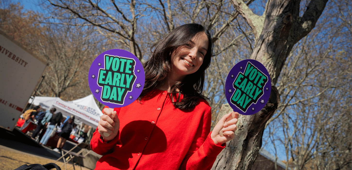 Staff members holding up vote early signs