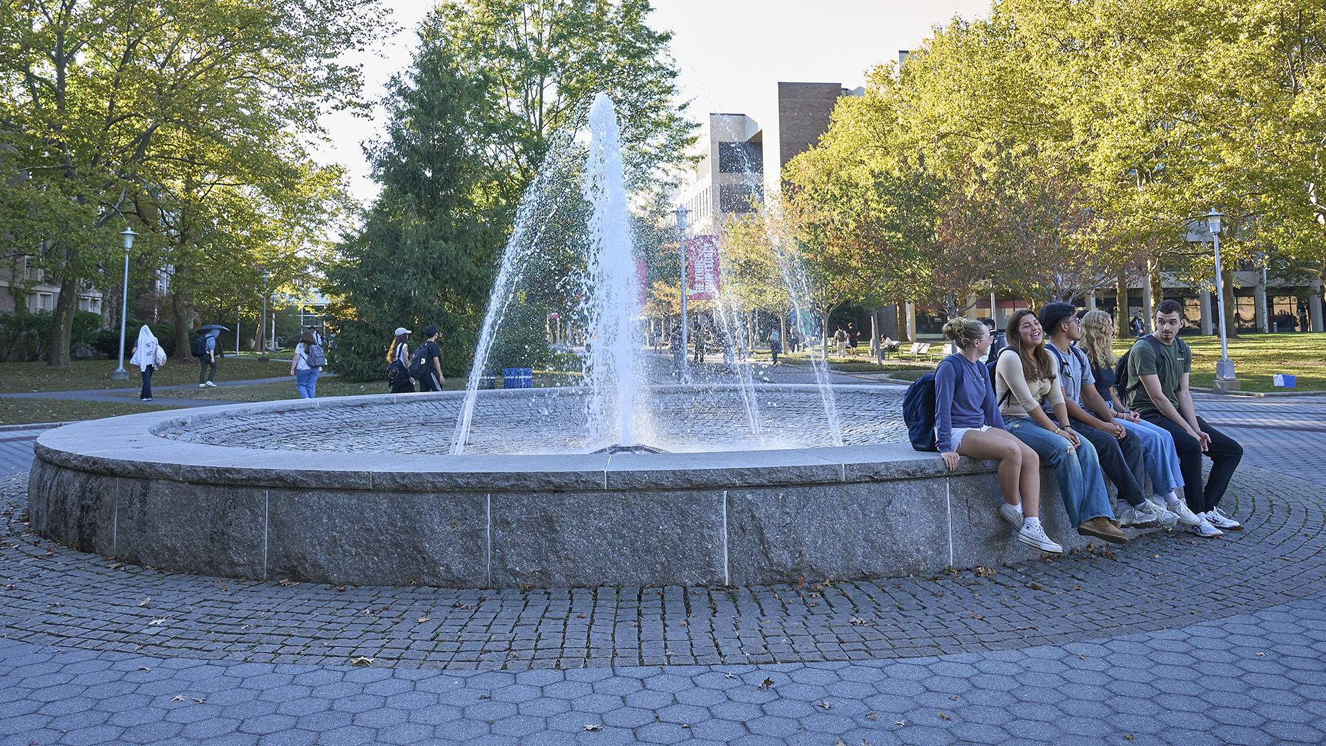 Students sitting beside a fountain.