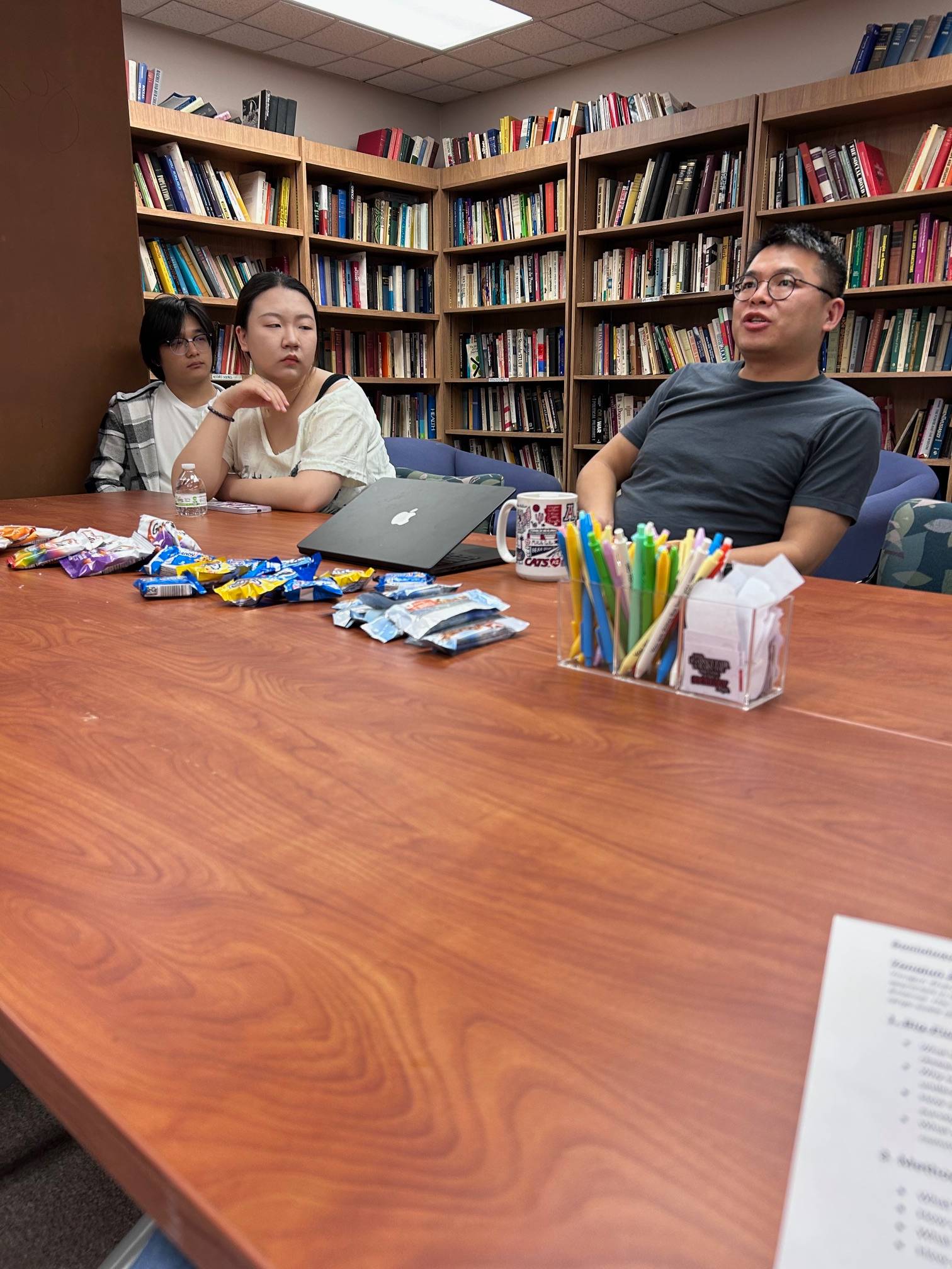 Professor and students engaged in a discussion in a library