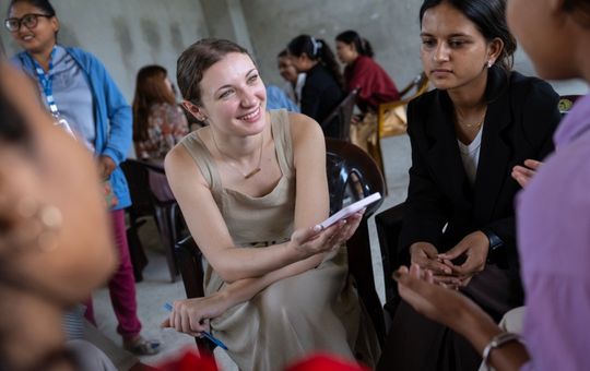 Student smiling while holding phone and conducting an interview.