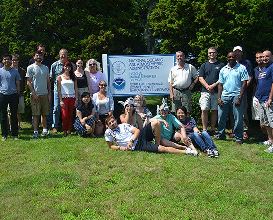 Sara Bailey with NOAA National Marine Fisheries Service colleagues surrounding a sign for the building.