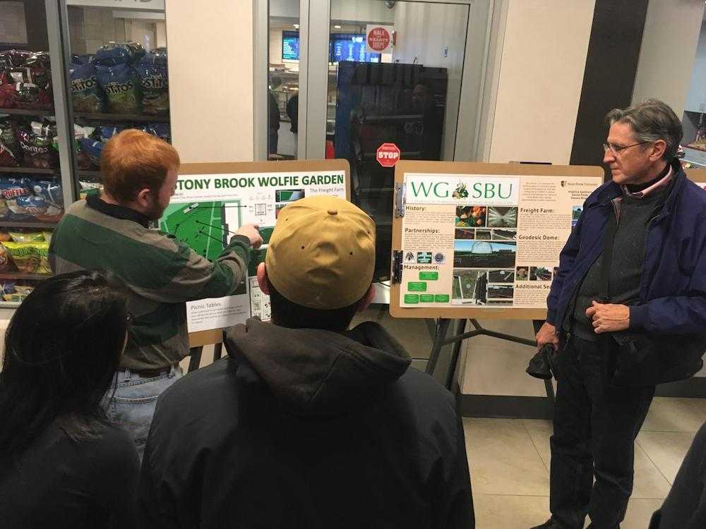 A student presents his poster of the Stony Brook Wolfie Garden to a visitor