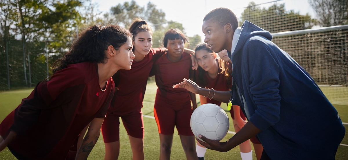 A soccer coach talking to her team mid-huddle