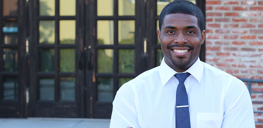 A school principal smiling in front of his building