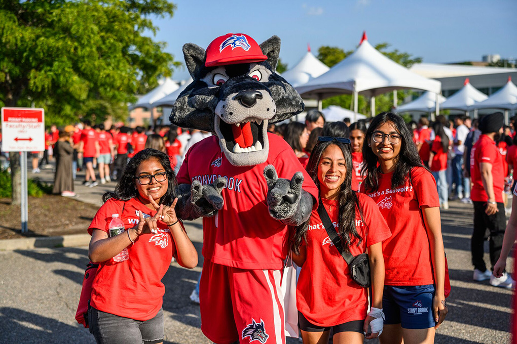 Students posing with campus mascot at an outdoor event.