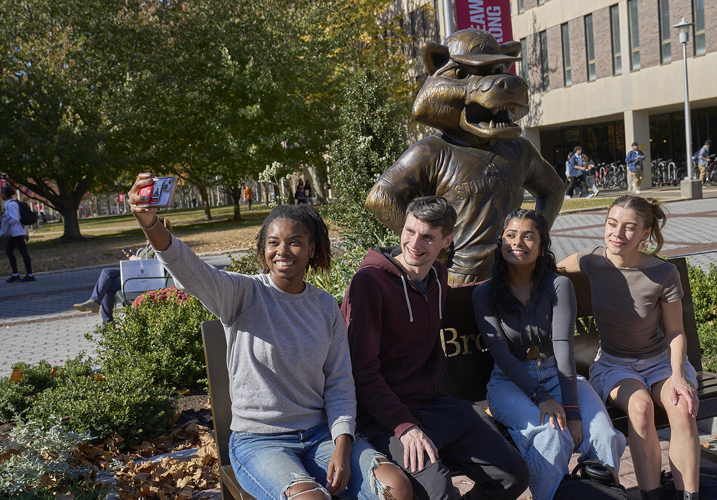 Group of students sitting together outdoors and smiling.