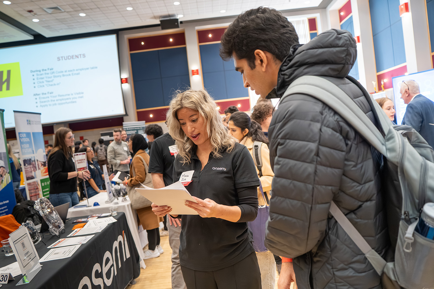 Student speaking with a representative at a campus career fair booth.