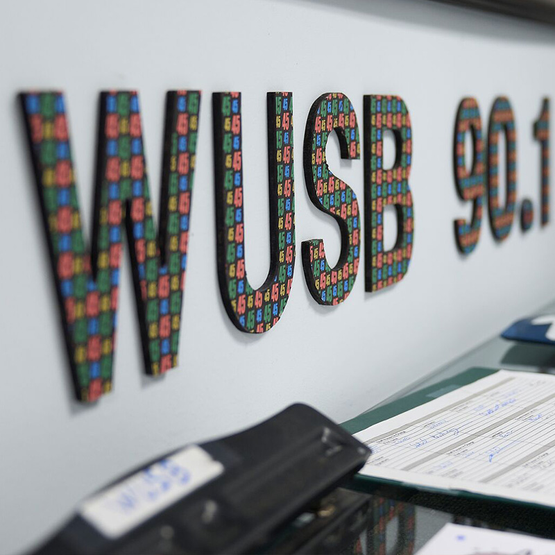 Multicolor letters spelling WUSB 90.1 on a white wall.