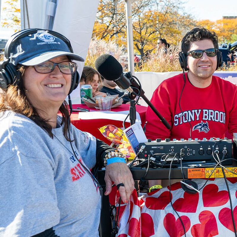 Students sitting at an outdoor table with recording gear.