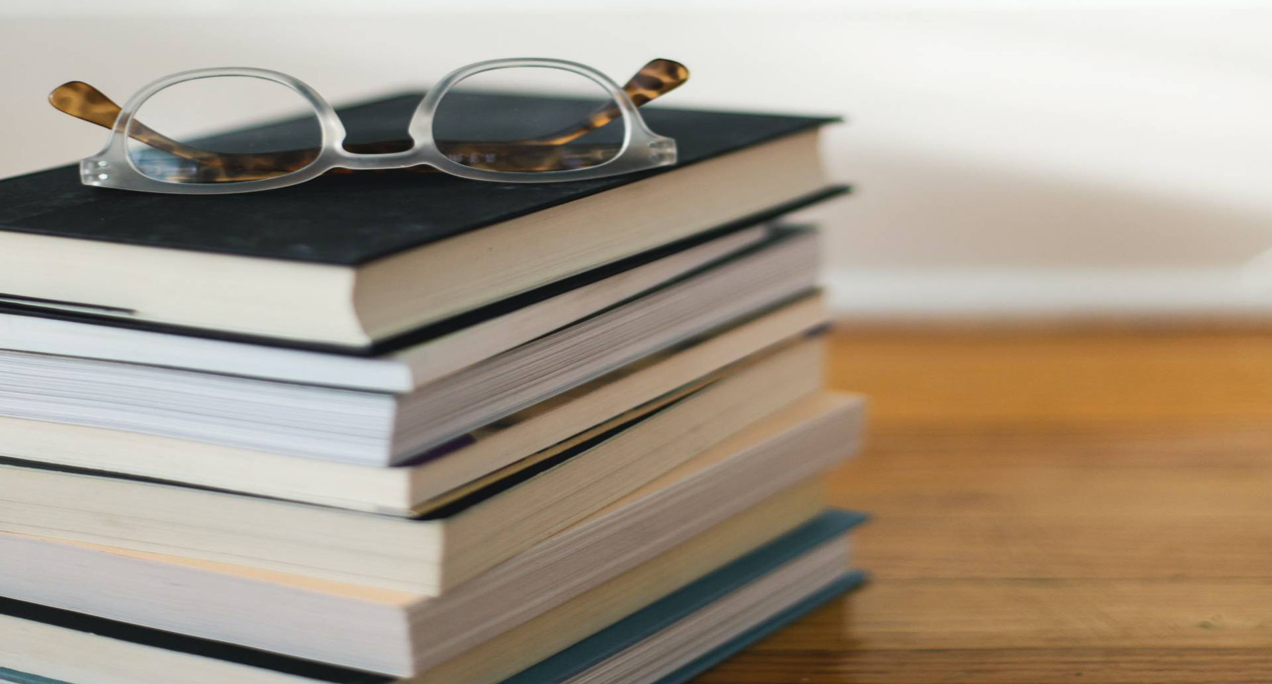 Stack of books with eyeglasses on top of them