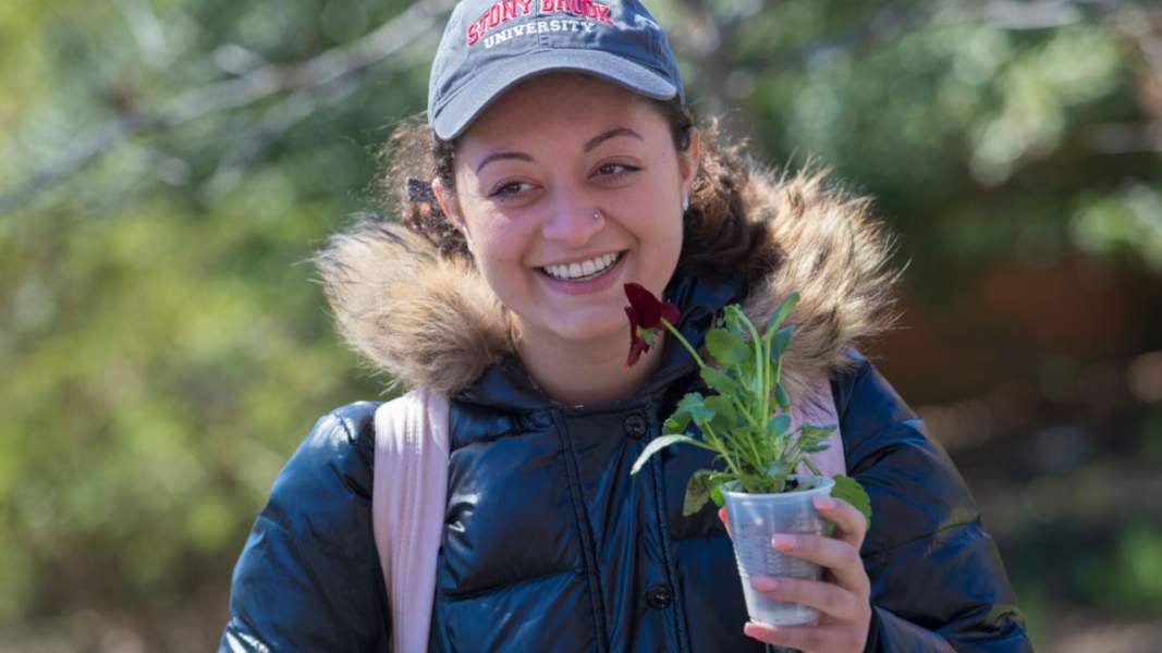 Student holds a cup of cut flowers