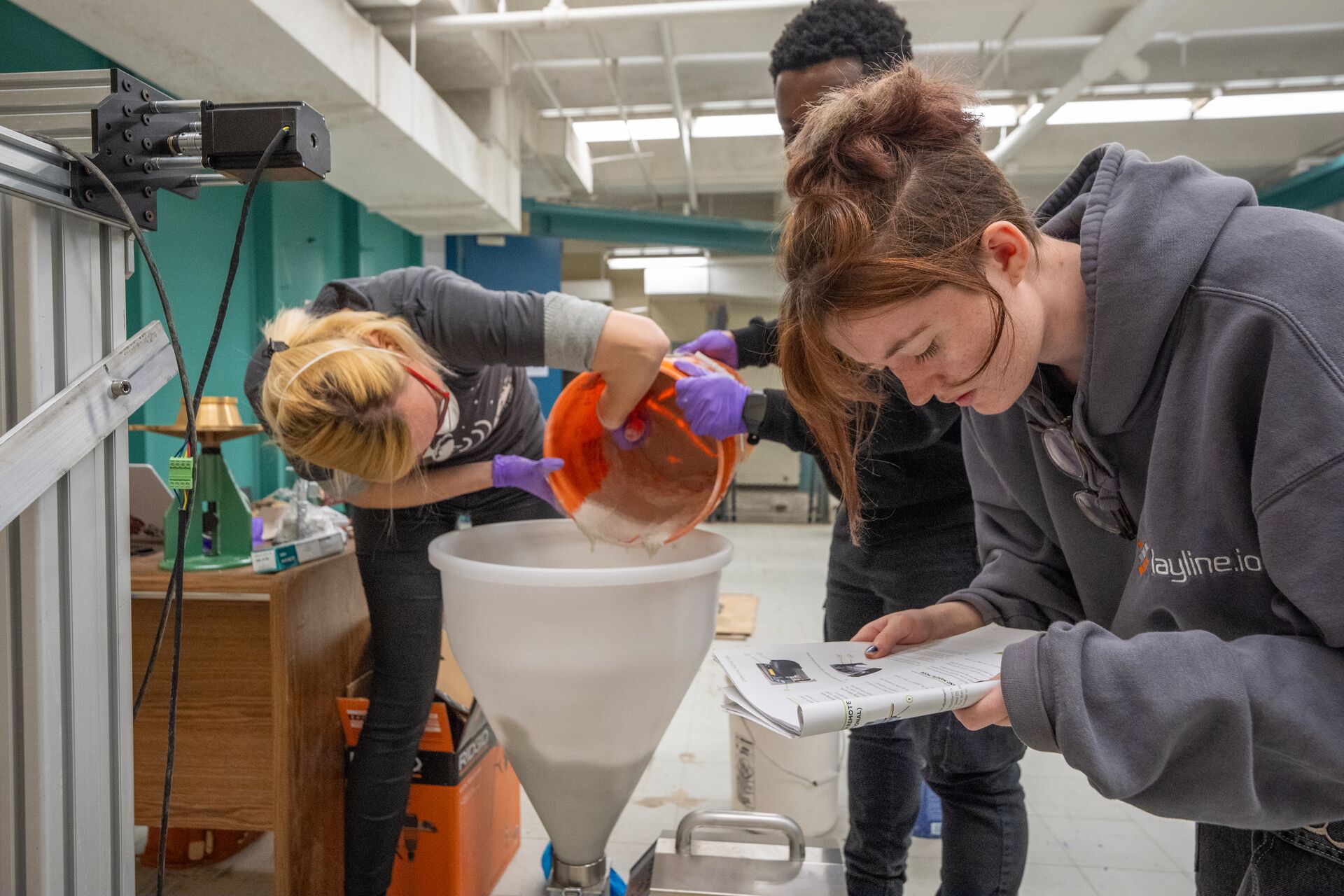 Students pouring concrete into a large funnel.
