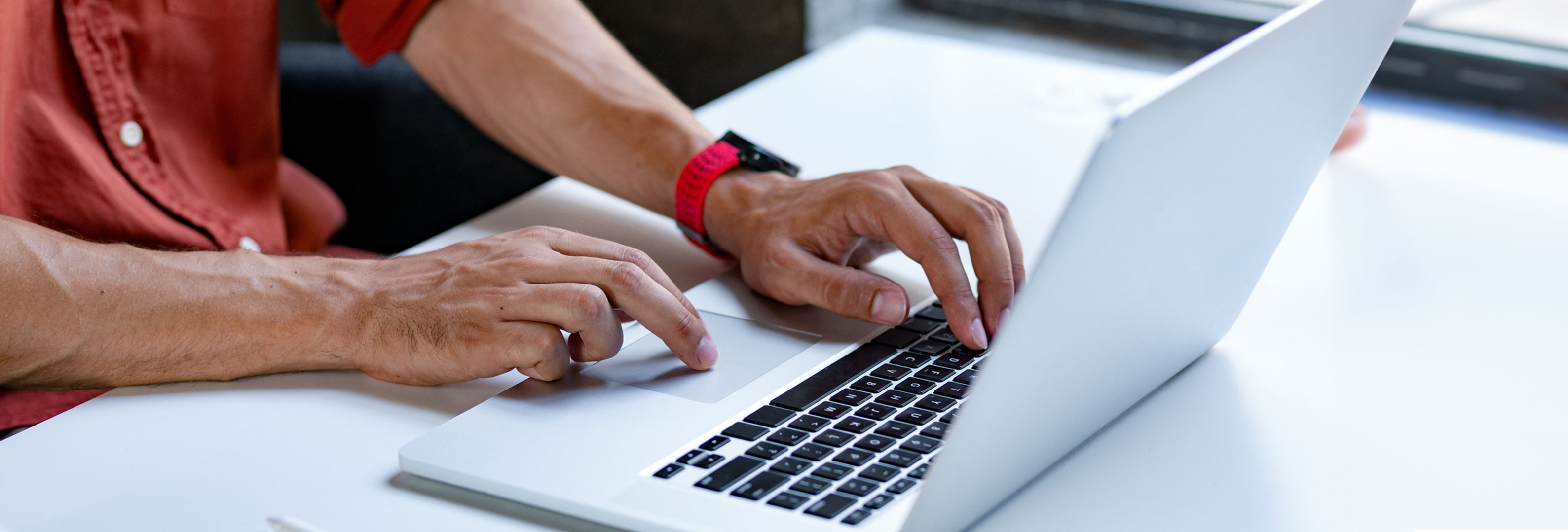 Man's hands typing and using the touchpad on a laptop